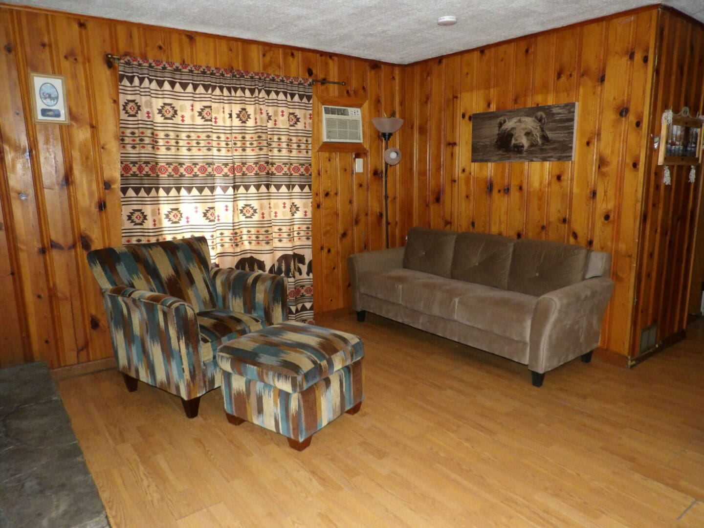A living room with wood paneling and wooden floors.