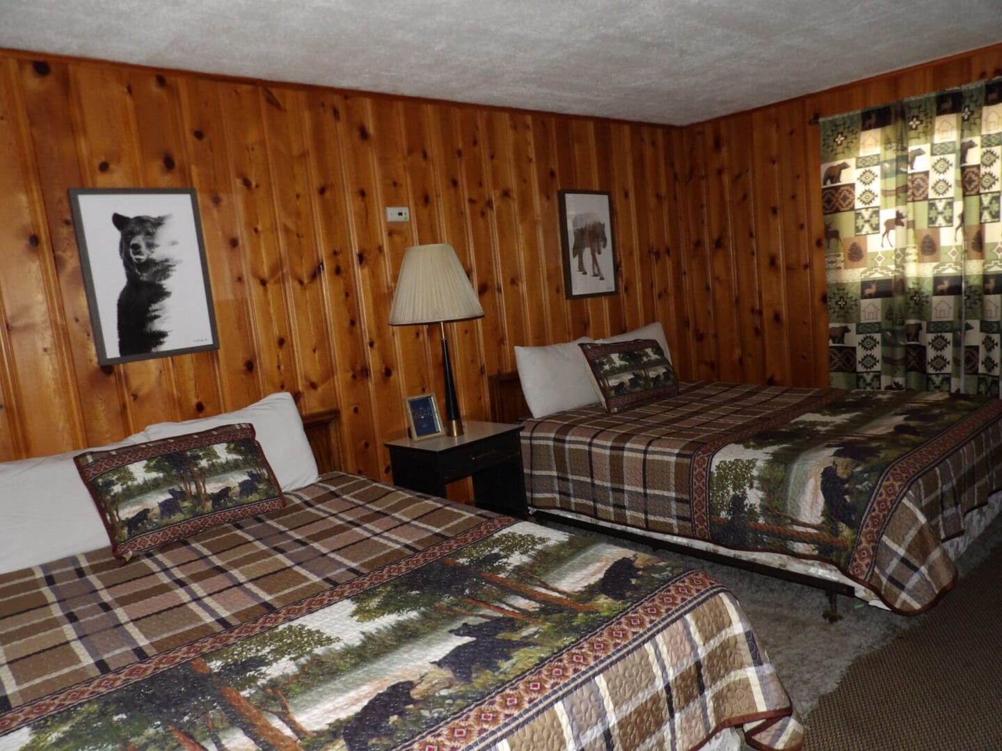 A bedroom with two beds and wood paneled walls.