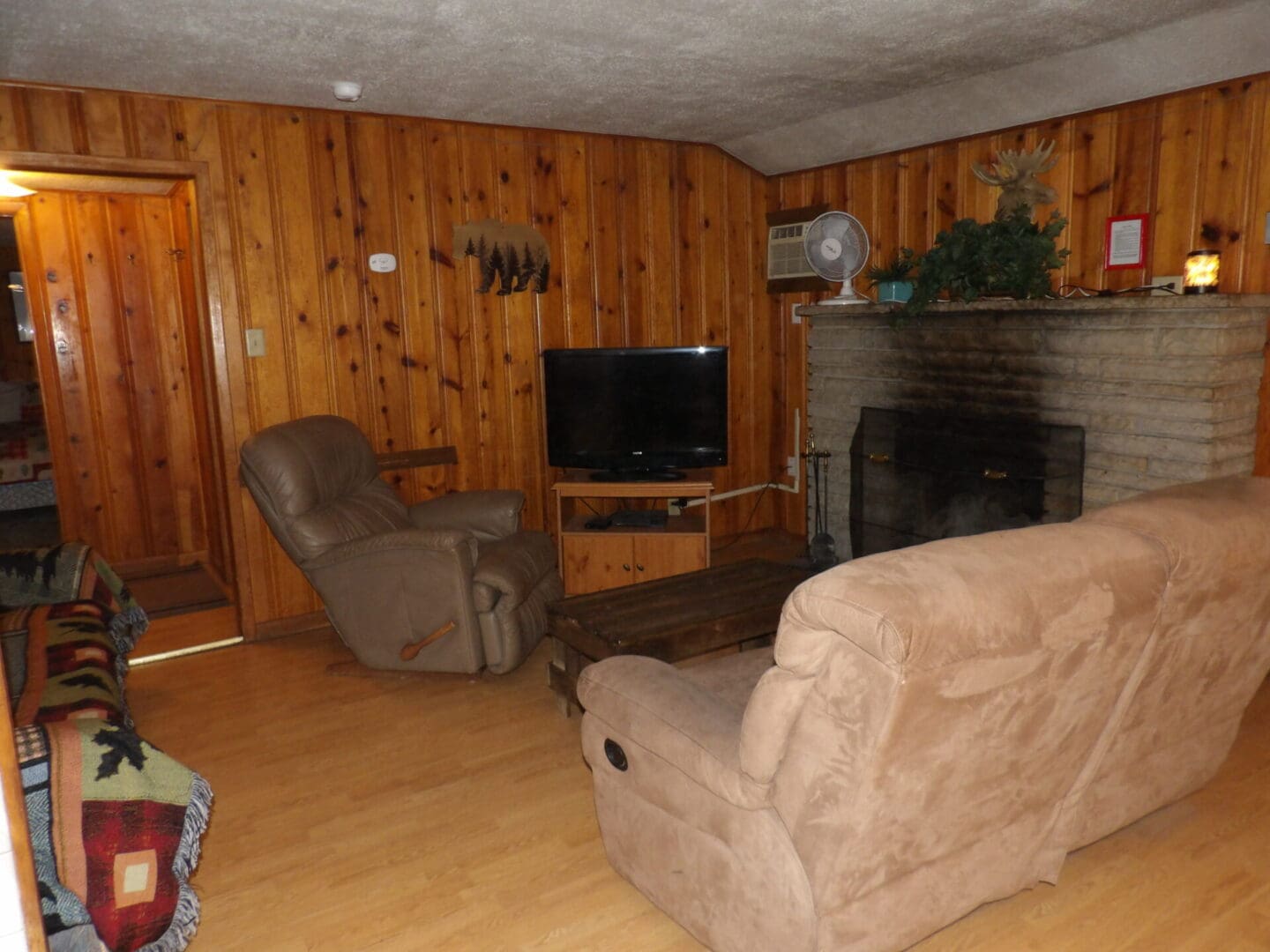 A living room with wood paneling and a fireplace.