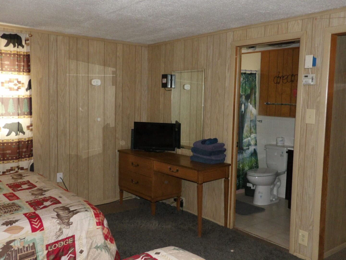 A room with a bed, desk and toilet in it.