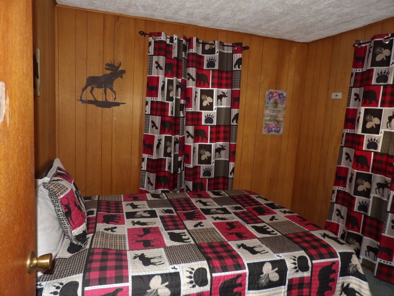A bedroom with a bed, two pillows and a moose on the wall.