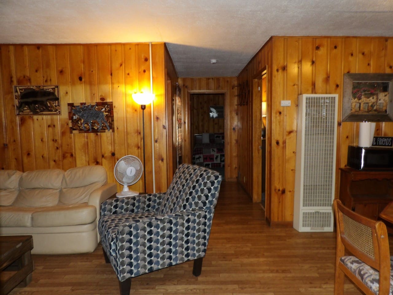A living room with wood paneled walls and hardwood floors.